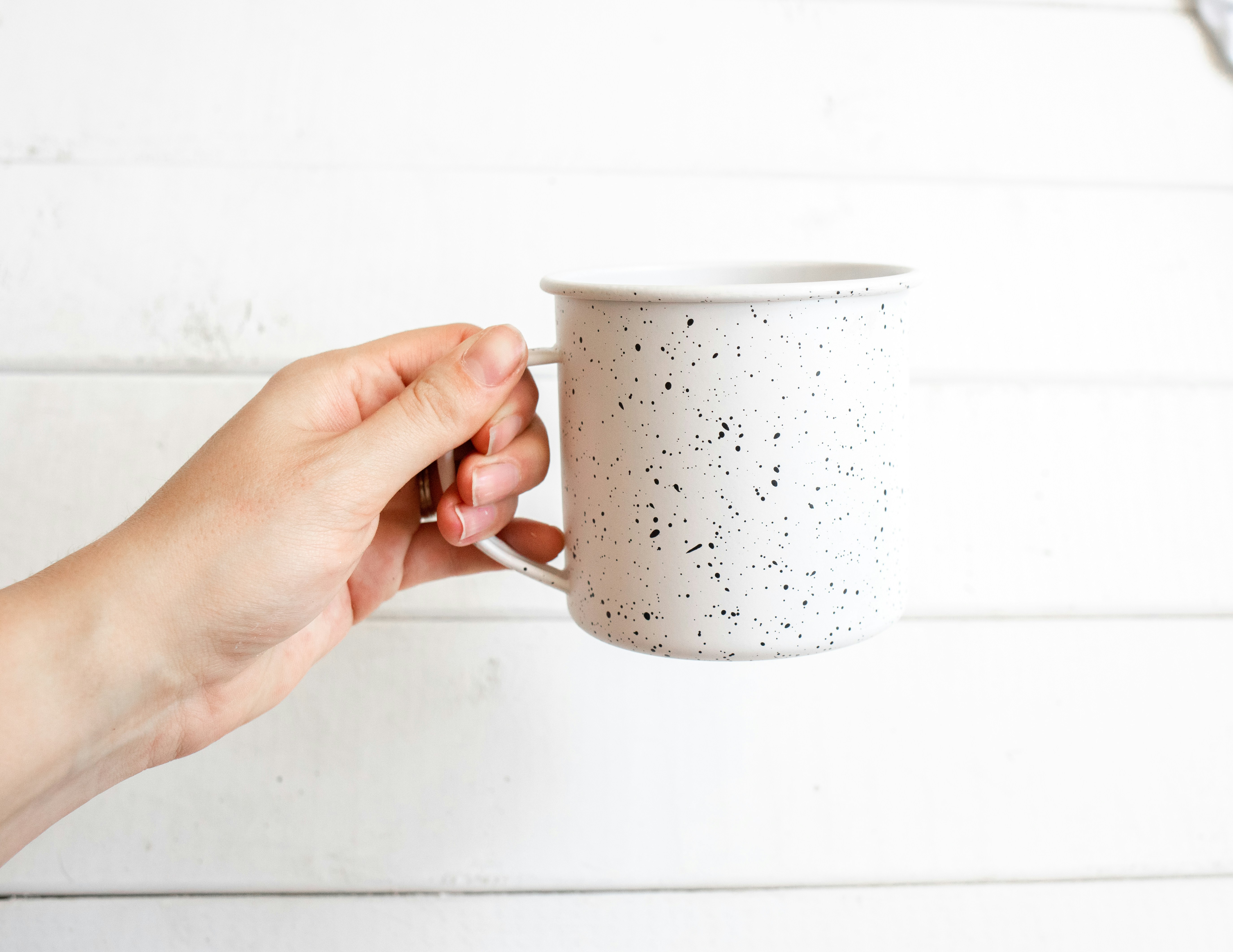 person holding white and black ceramic mug