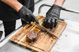 Chef’s hands seasoning freshly cut steak with spices in a rustic kitchen.