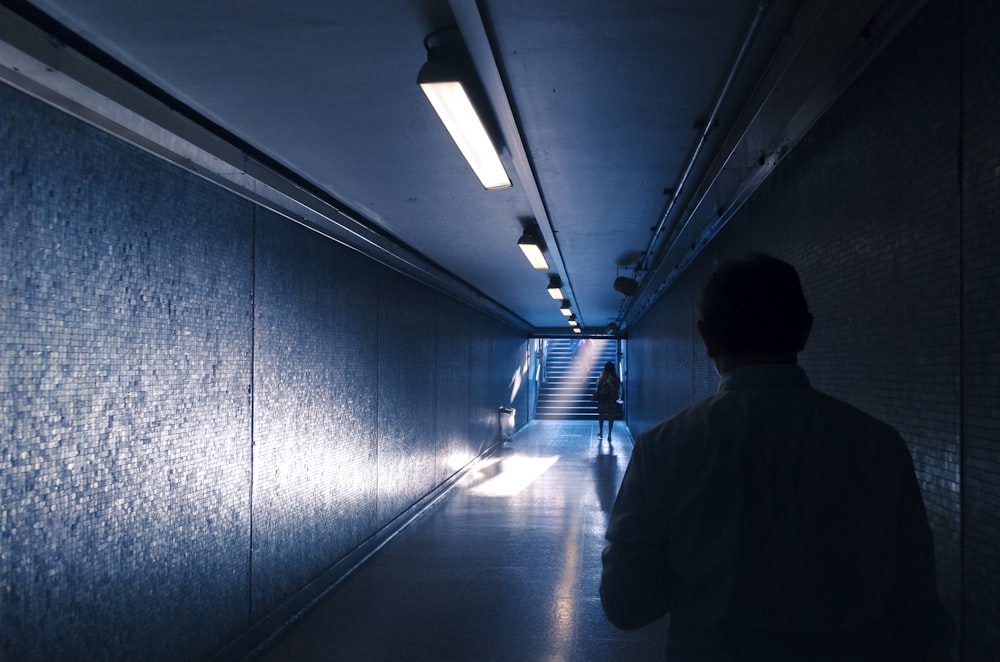 man in black jacket walking on hallway