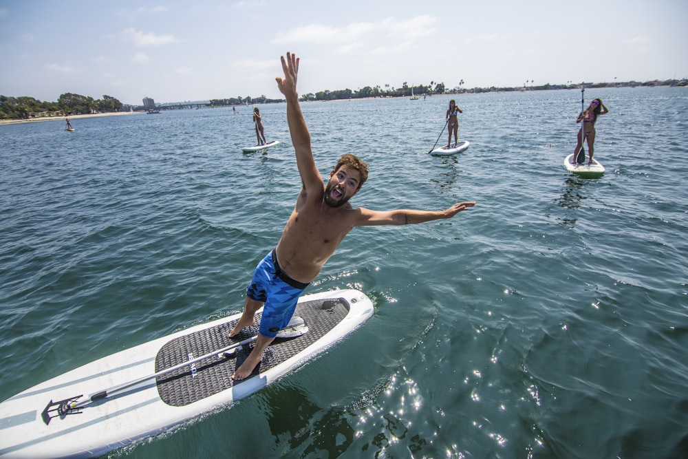 man in blue shorts sitting on white and black boat during daytime