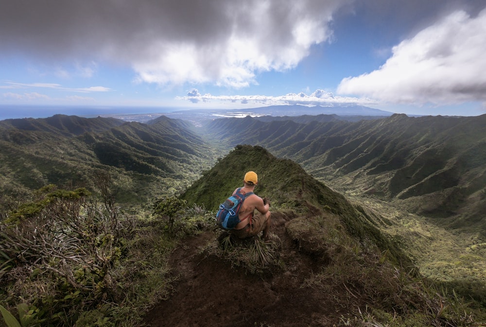 man in blue jacket sitting on brown rock during daytime