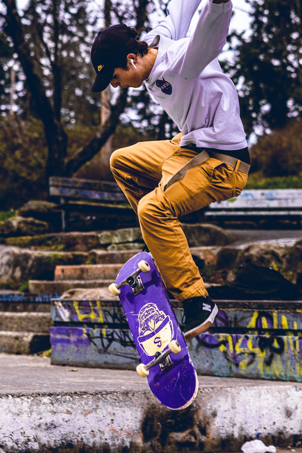 homem em camisa branca de manga comprida e calças marrons andando de skate durante o dia