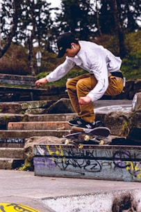 man in white long sleeve shirt and brown pants sitting on black metal fence during daytime
