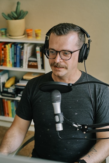 Erik Hatfield recording a podcast episode in a cozy home studio filled with books and warm lighting.