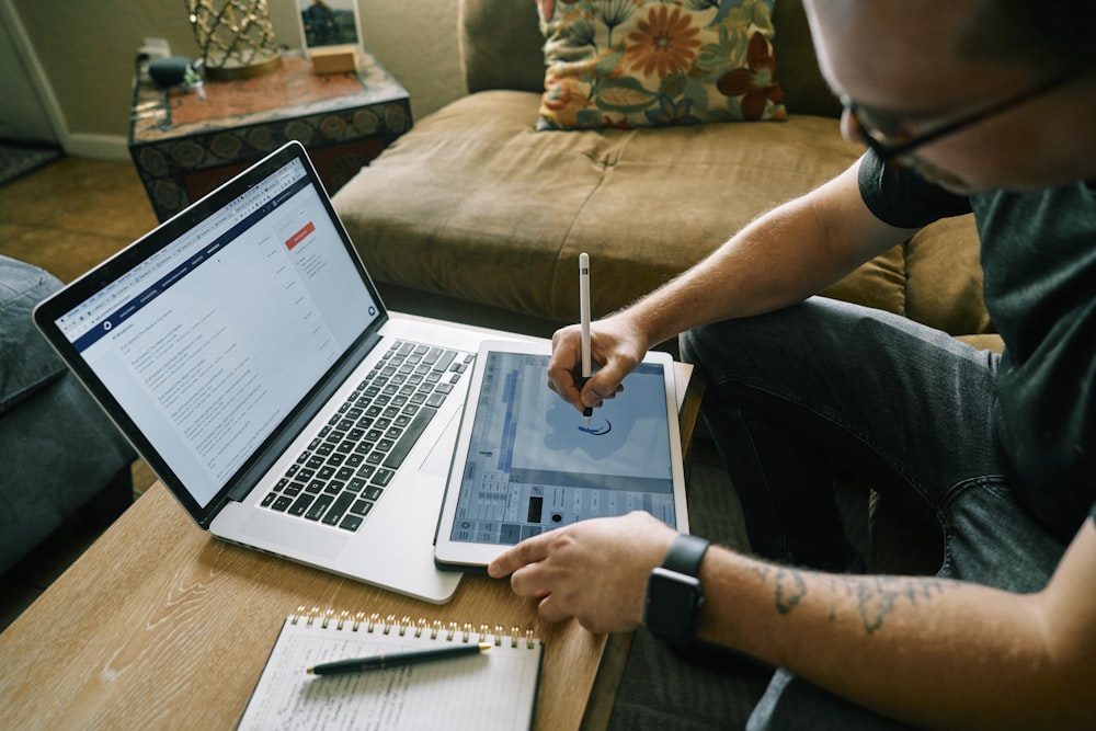 person holding pen and macbook air