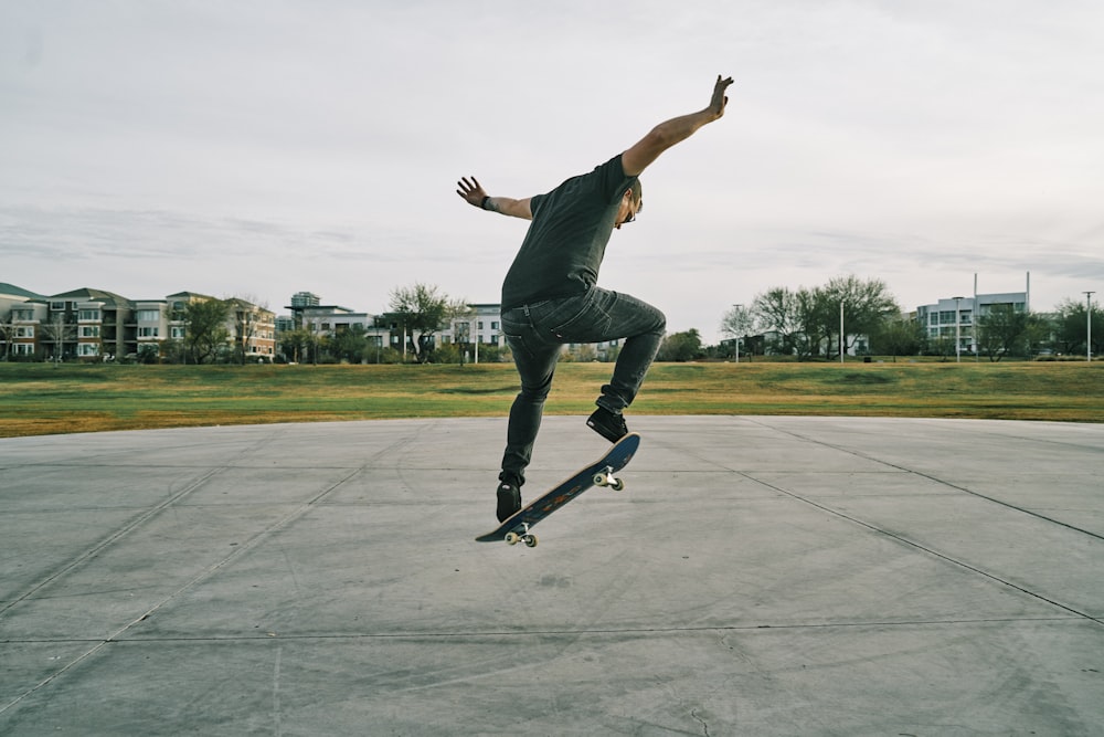 man in black t-shirt and blue denim jeans riding skateboard during daytime