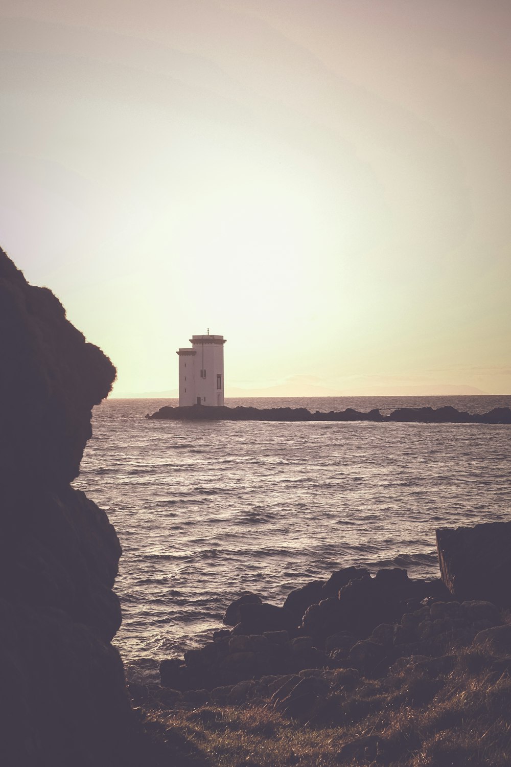 white concrete building on rock formation near sea during daytime