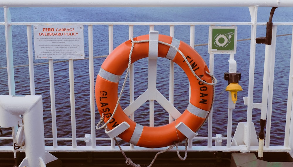 orange life buoy on white steel fence during daytime