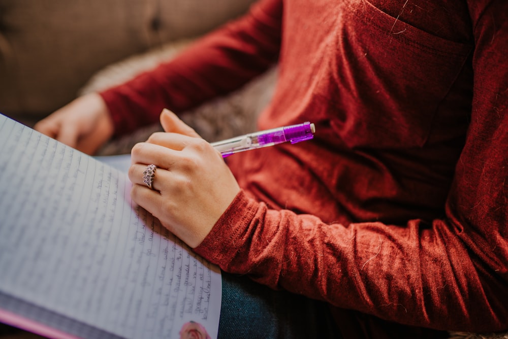 person in red long sleeve shirt holding pen