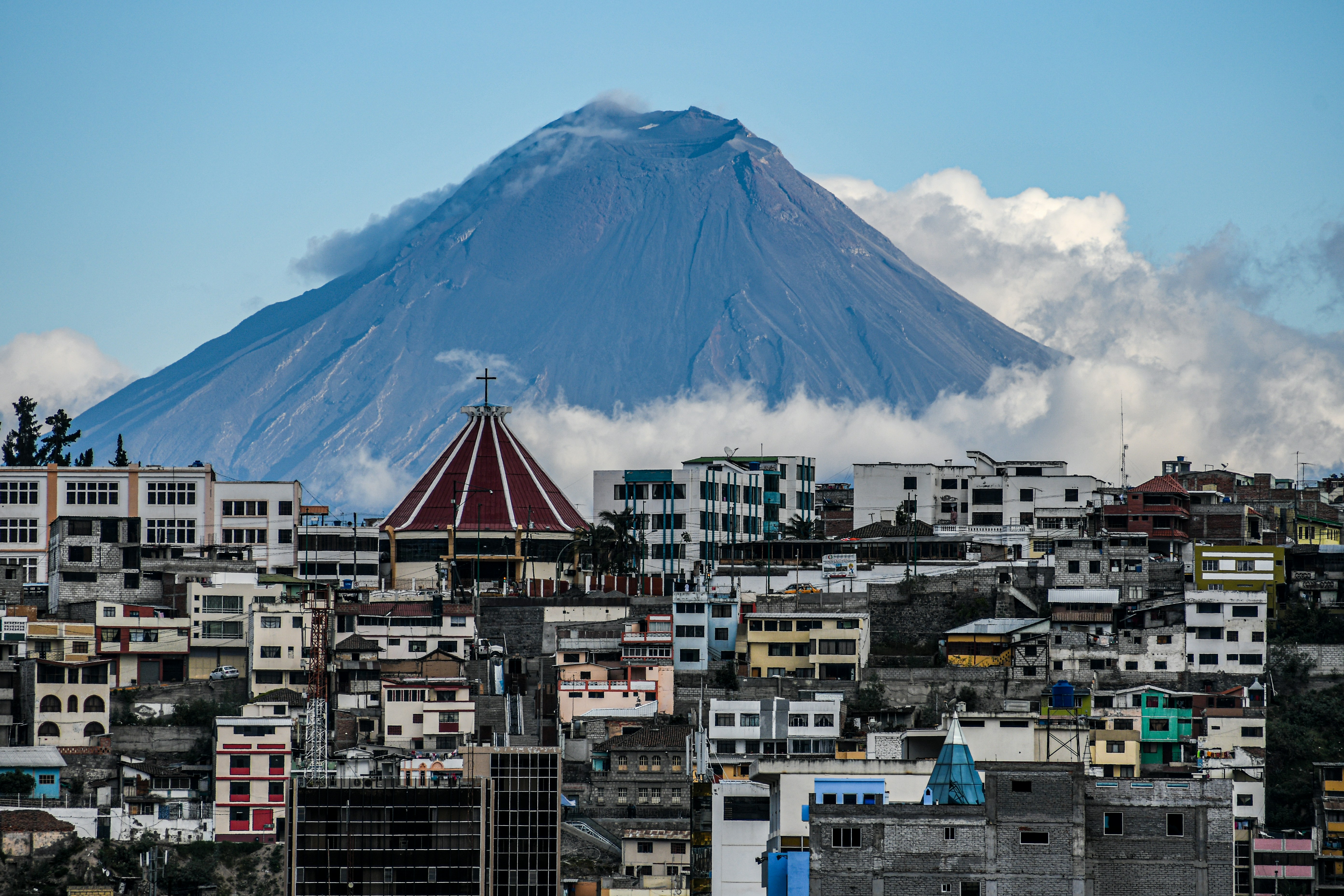 white and brown concrete buildings near mountain under white clouds during daytime