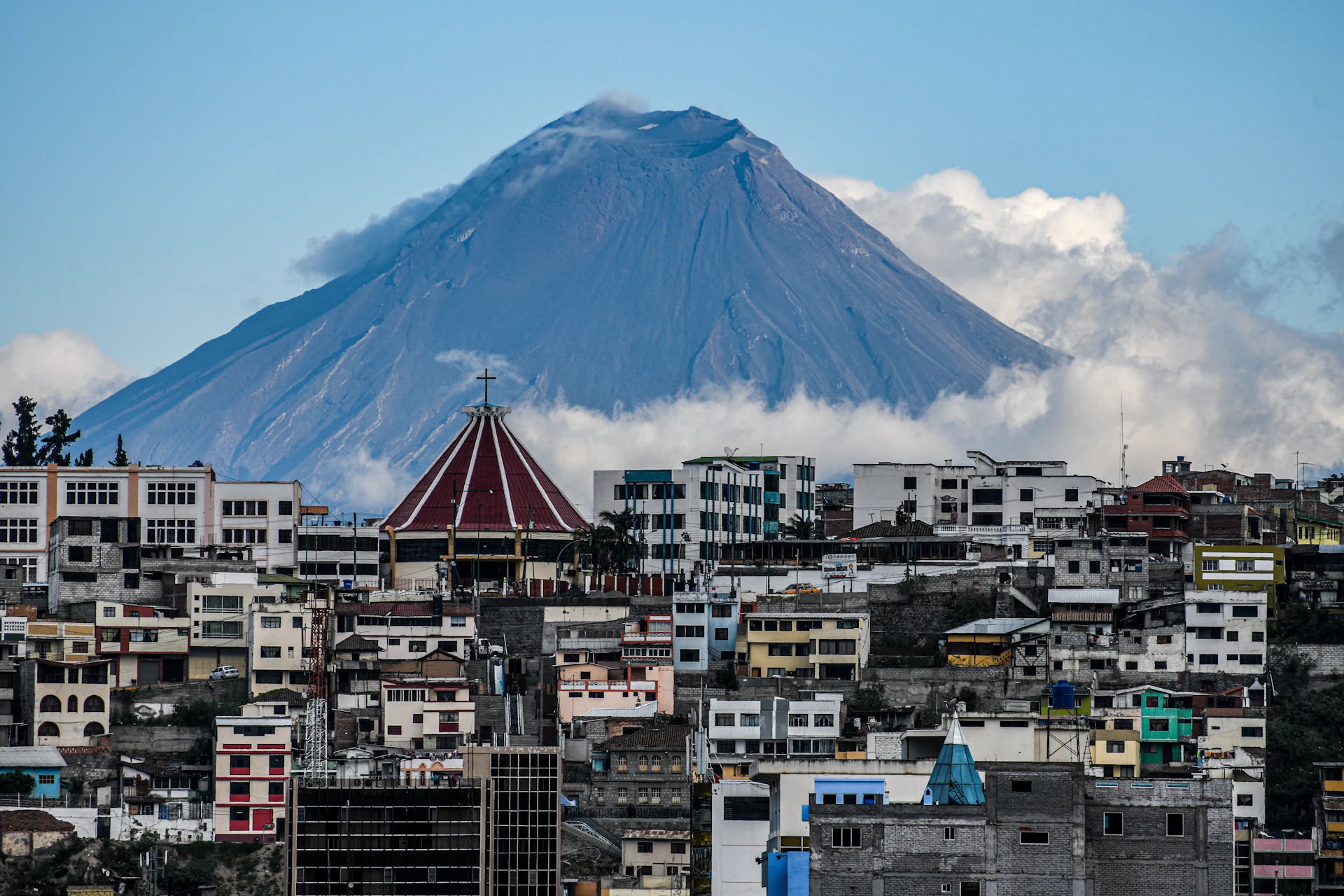white and brown concrete buildings near mountain under white clouds during daytime