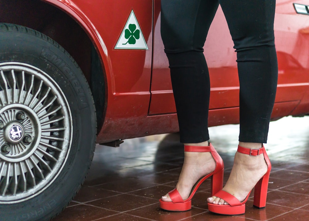 Foto Mujer con pantalones negros y zapatos bajos rojos al lado un auto rojo – Imagen en Unsplash