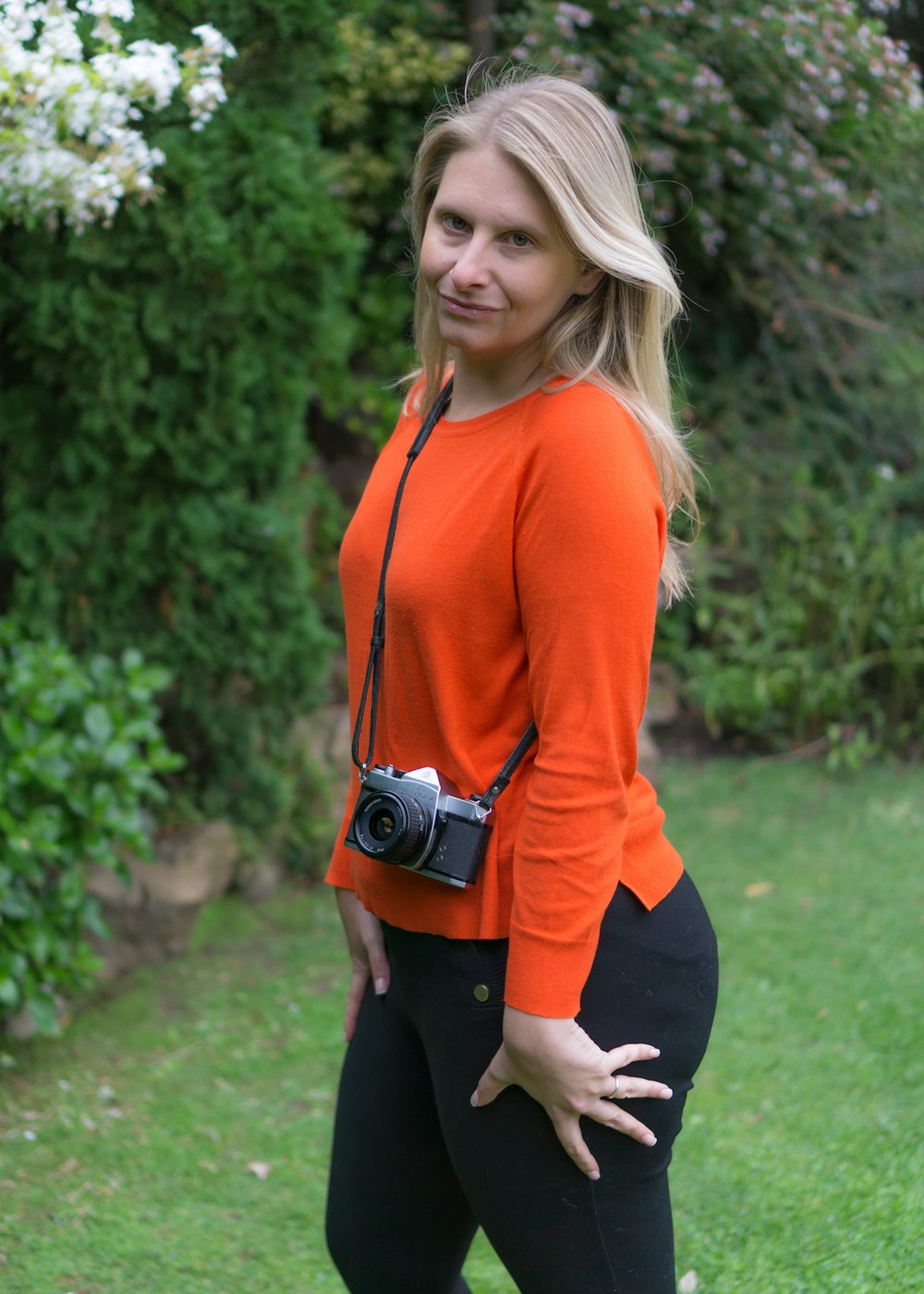 woman in red long sleeve shirt and black pants standing on green grass field during daytime