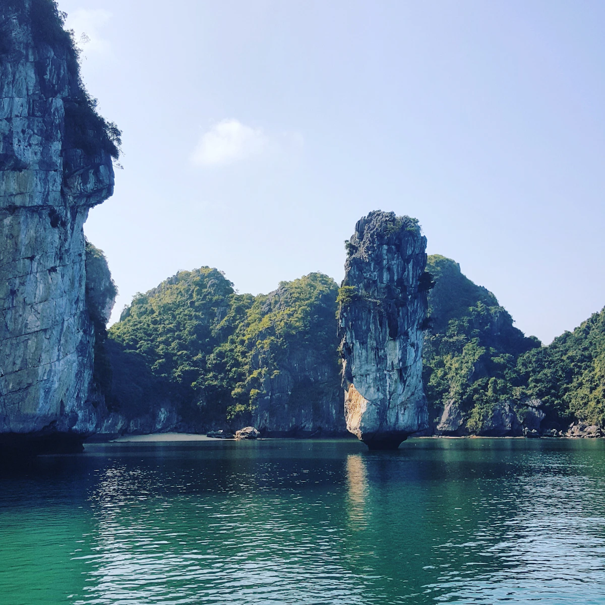 Limestone rock formations rising from calm water