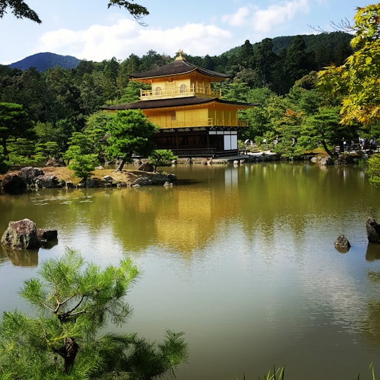 brown wooden house near lake and green trees during daytime in Kinkaku-ji Japan