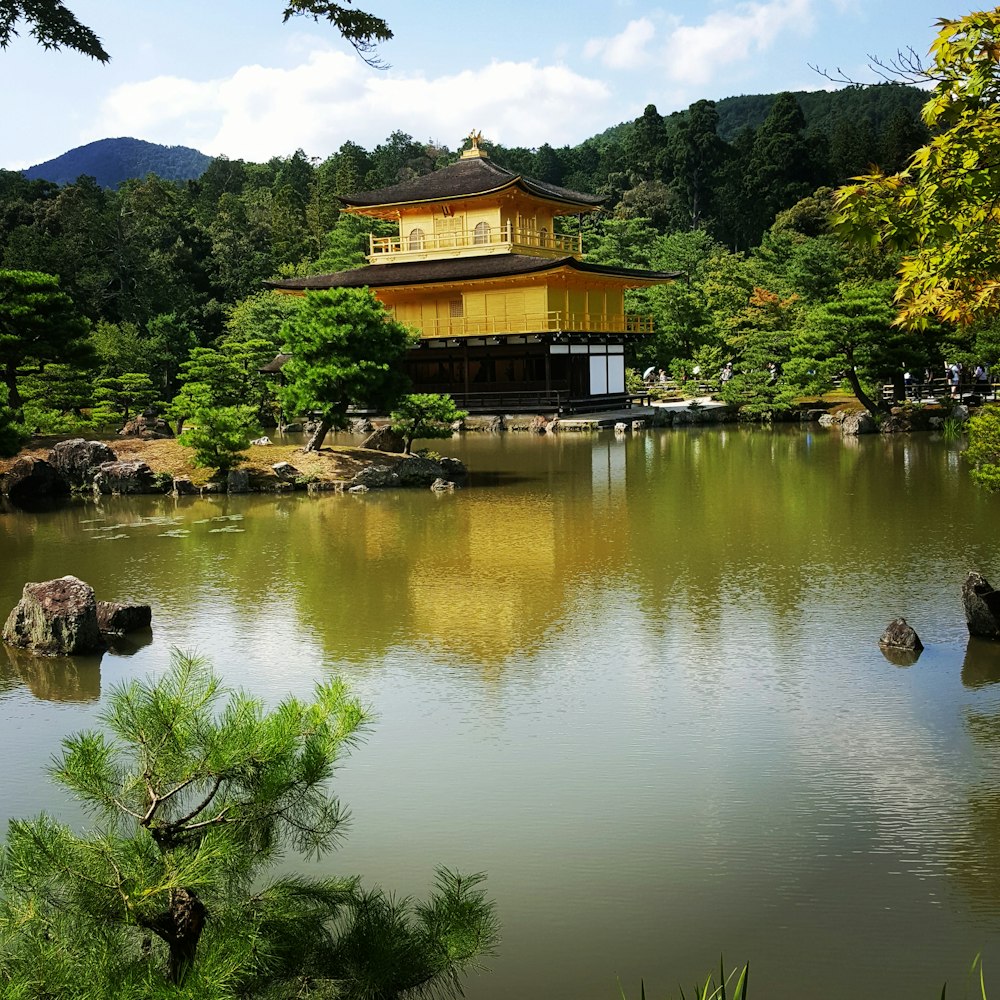 brown wooden house near lake and green trees during daytime