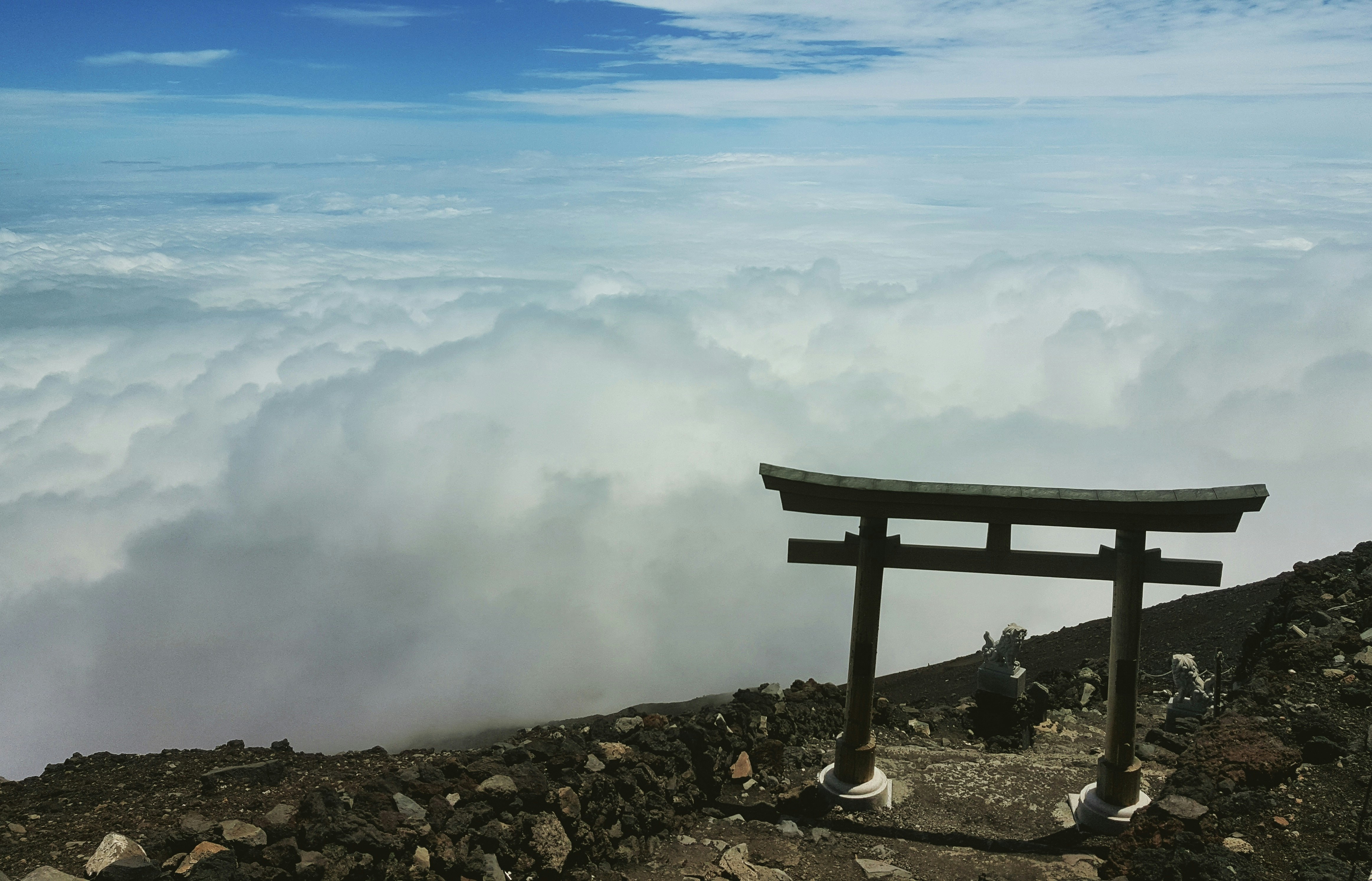 brown wooden bench on rocky shore under white clouds and blue sky during daytime