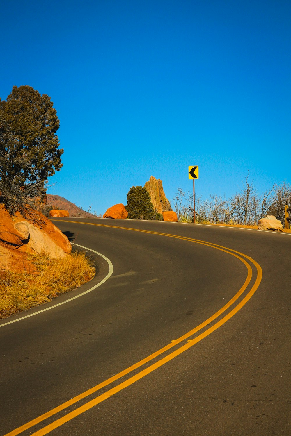 black asphalt road between brown grass field during daytime