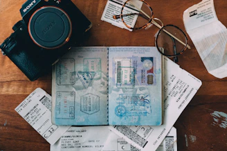 Close-up of compact, portable travel gadgets laid out on a wooden table with a passport and sunglasses.