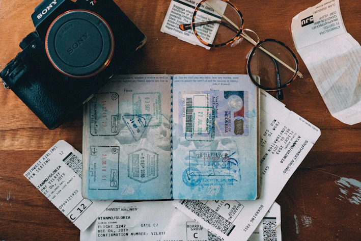 Close-up of compact, portable travel gadgets laid out on a wooden table with a passport and sunglasses.