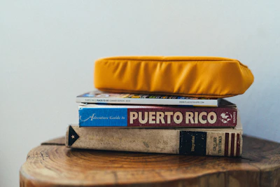 Stack of colorful cruise travel ebooks with a navy blue and gold nautical design on a wooden table.