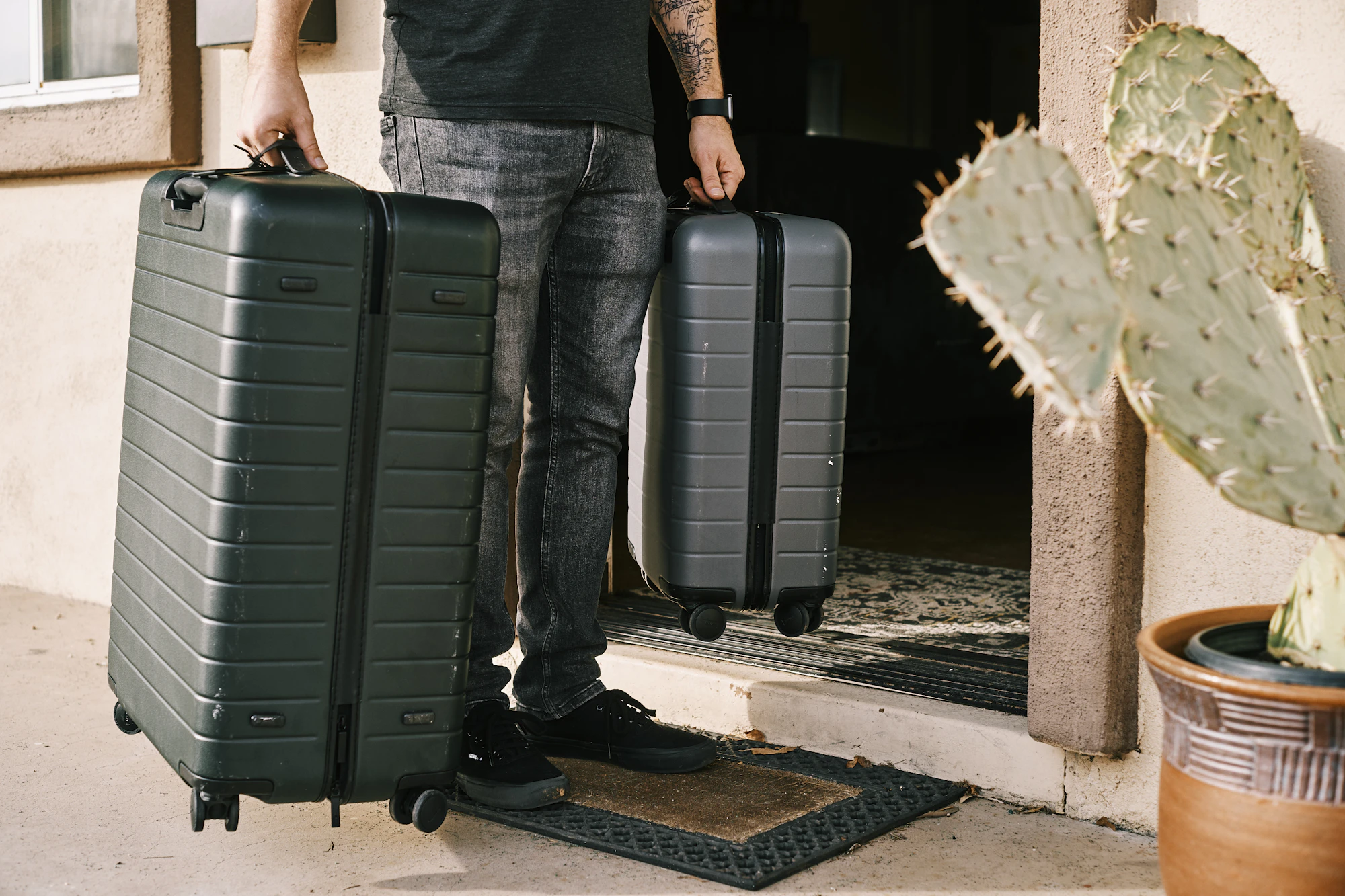 Traveller wheeling two hard-shell suitcases out through a doorway
