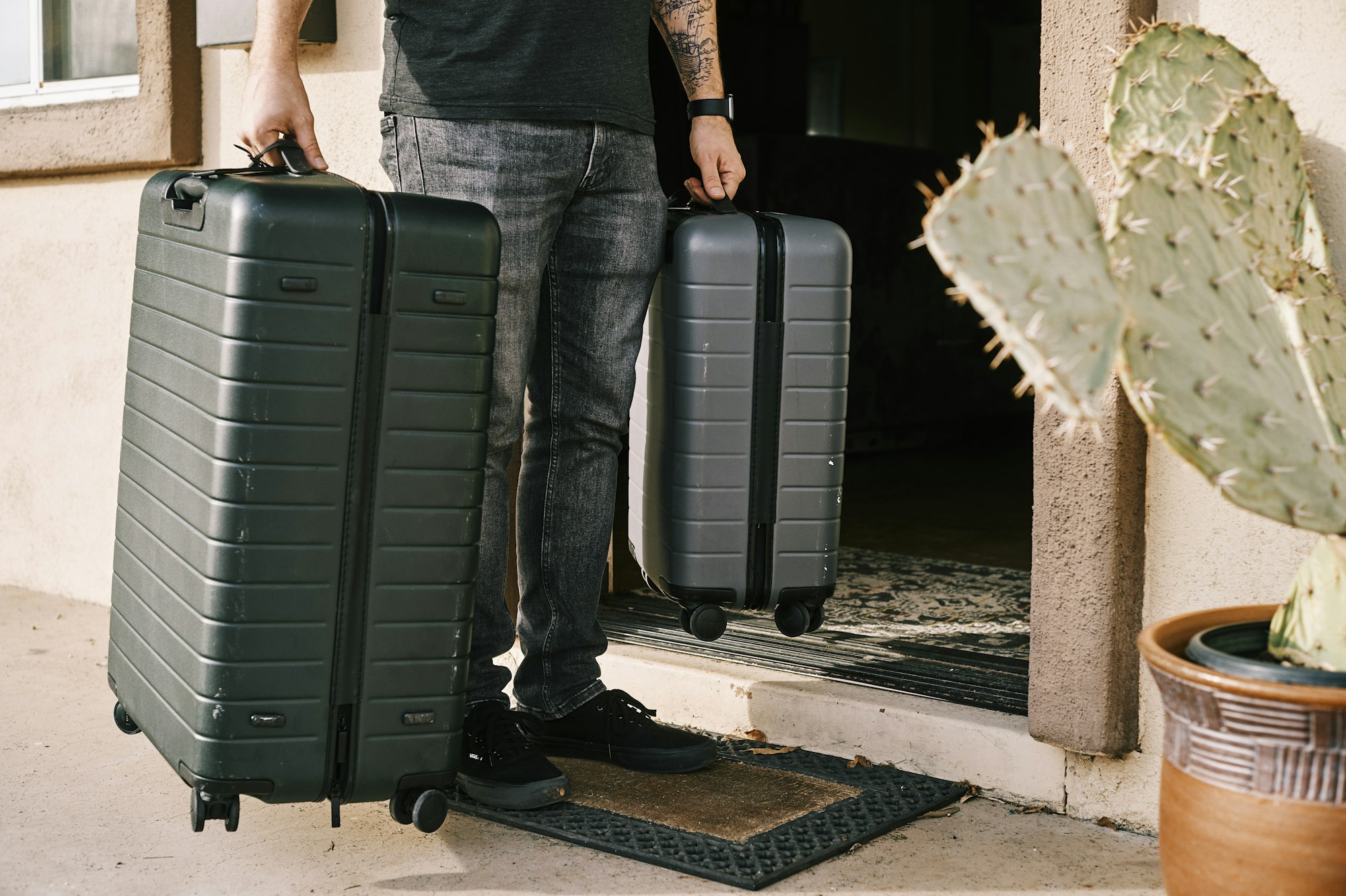 Traveller wheeling two hard-shell suitcases out through a doorway
