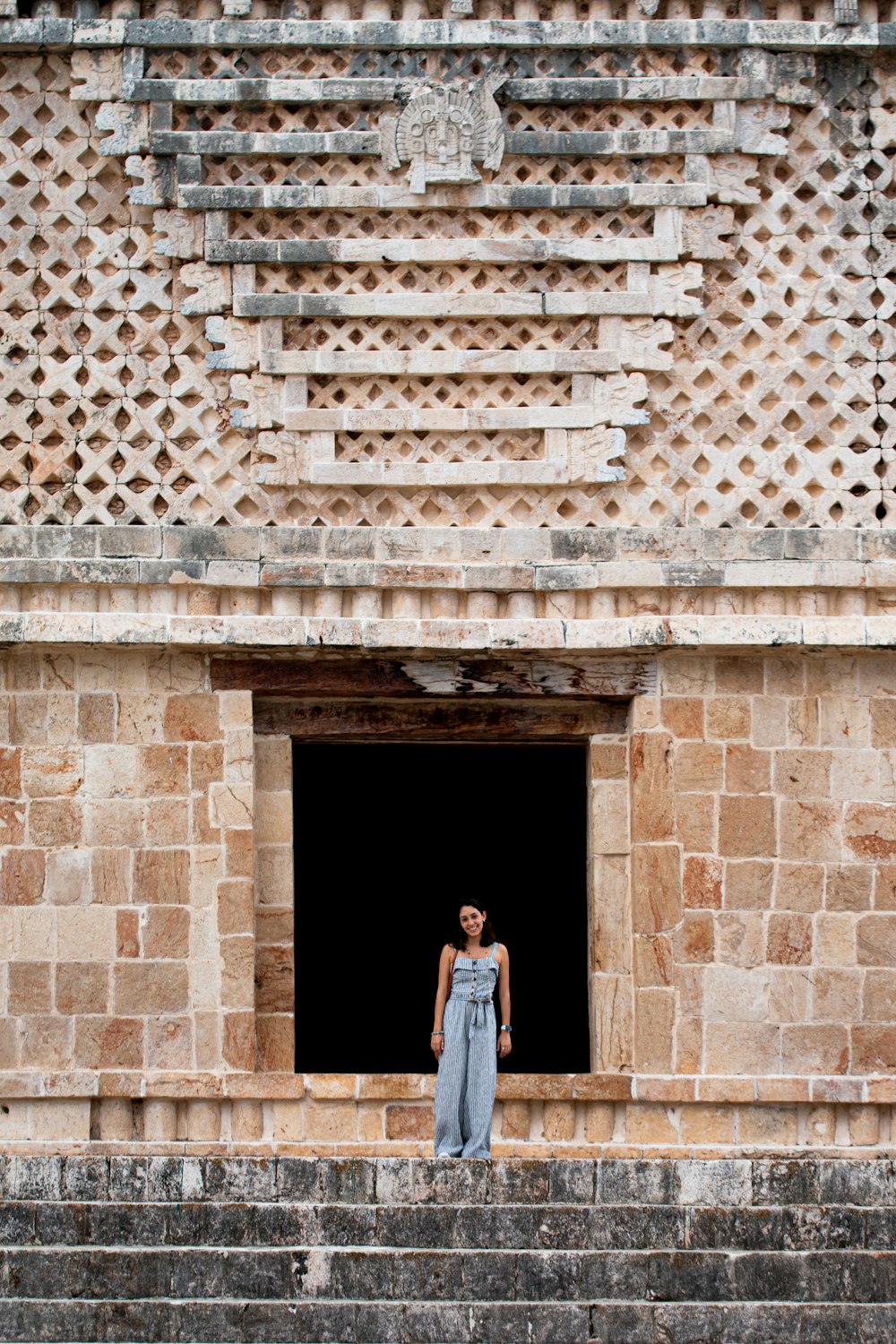 woman in blue dress standing on brown concrete building during daytime