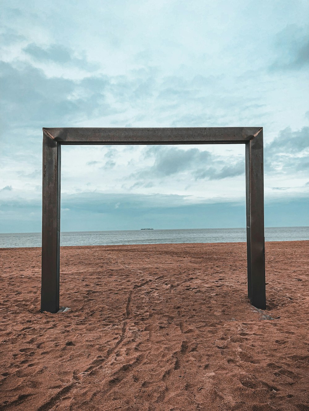 brown wooden frame on brown sand near body of water during daytime