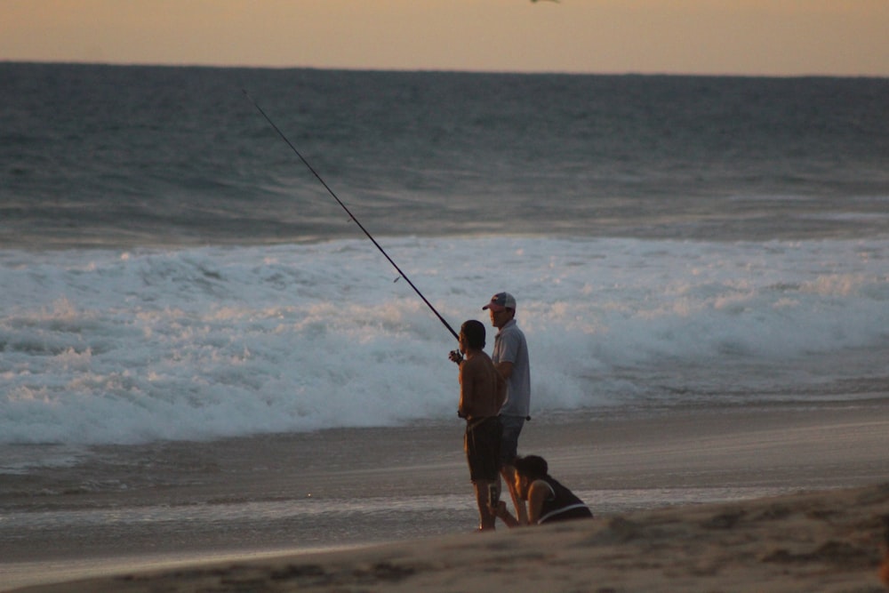 Mann und Frau mit Angelruten, die tagsüber am Strand spazieren gehen