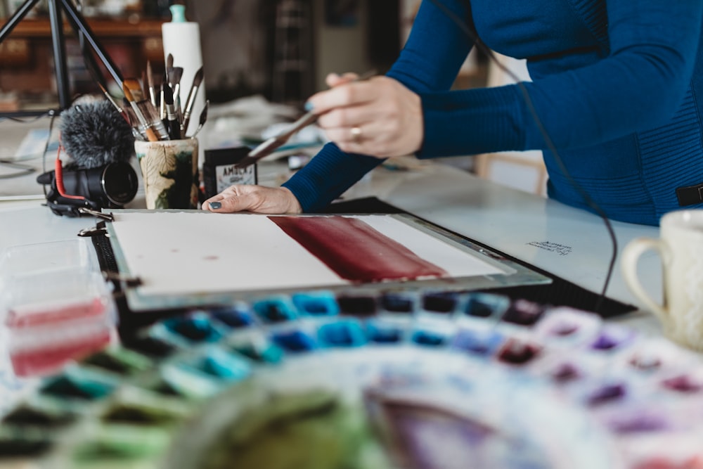 person in blue long sleeve shirt holding paint brush