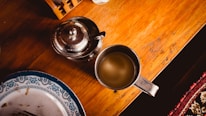 A close-up of a rustic wooden table set with vibrant dishes and a steaming cup of tea.