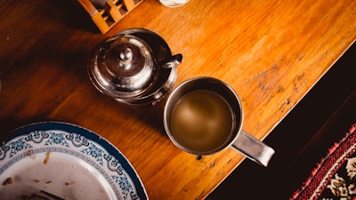 A close-up of a rustic wooden table set with vibrant dishes and a steaming cup of tea.