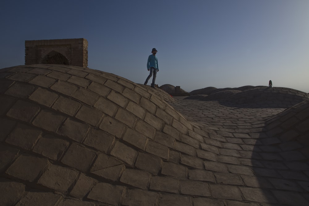 man in blue jacket standing on brown rock formation during daytime