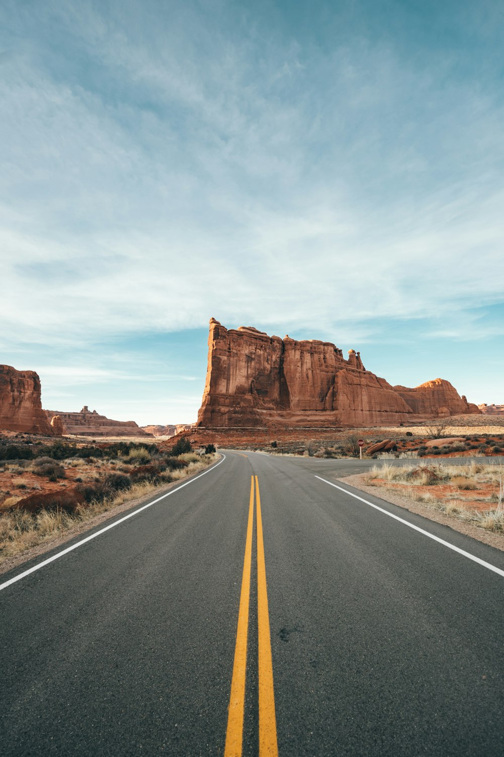 brown rock formation beside gray asphalt road during daytime