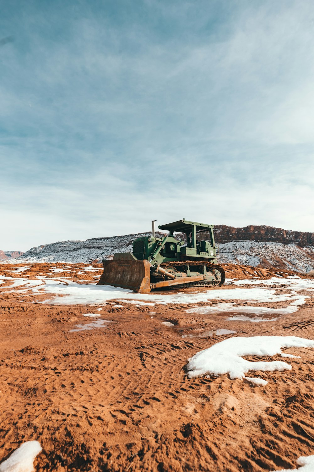 green and black heavy equipment on brown field under white clouds during daytime