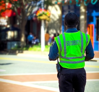 man in green and blue jacket walking on street during daytime