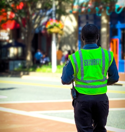 man in green and blue jacket walking on street during daytime