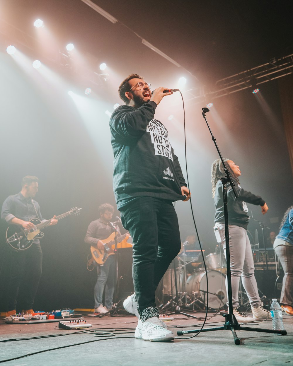 man in black and white striped long sleeve shirt singing on stage