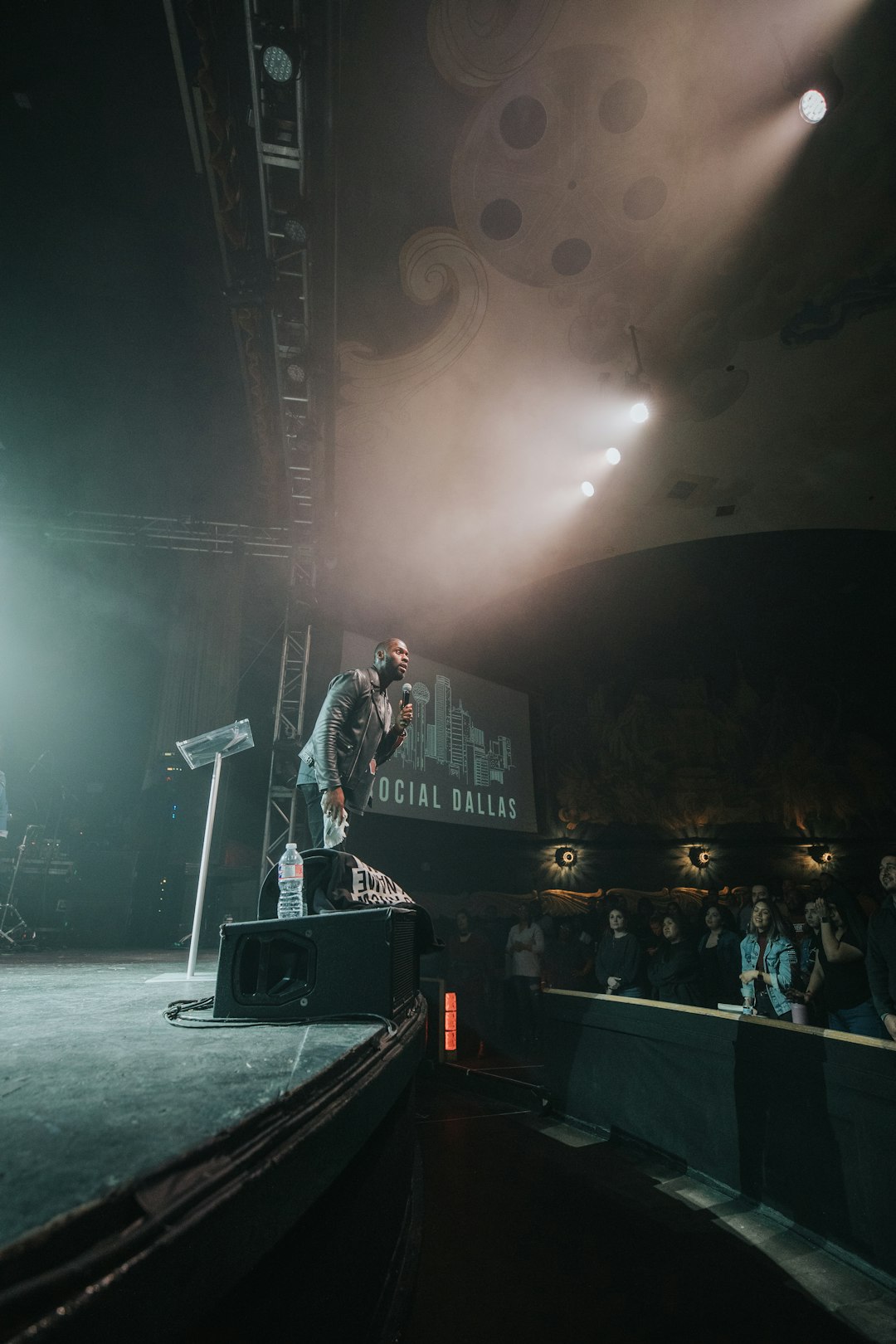 man in black and white jacket singing on stage