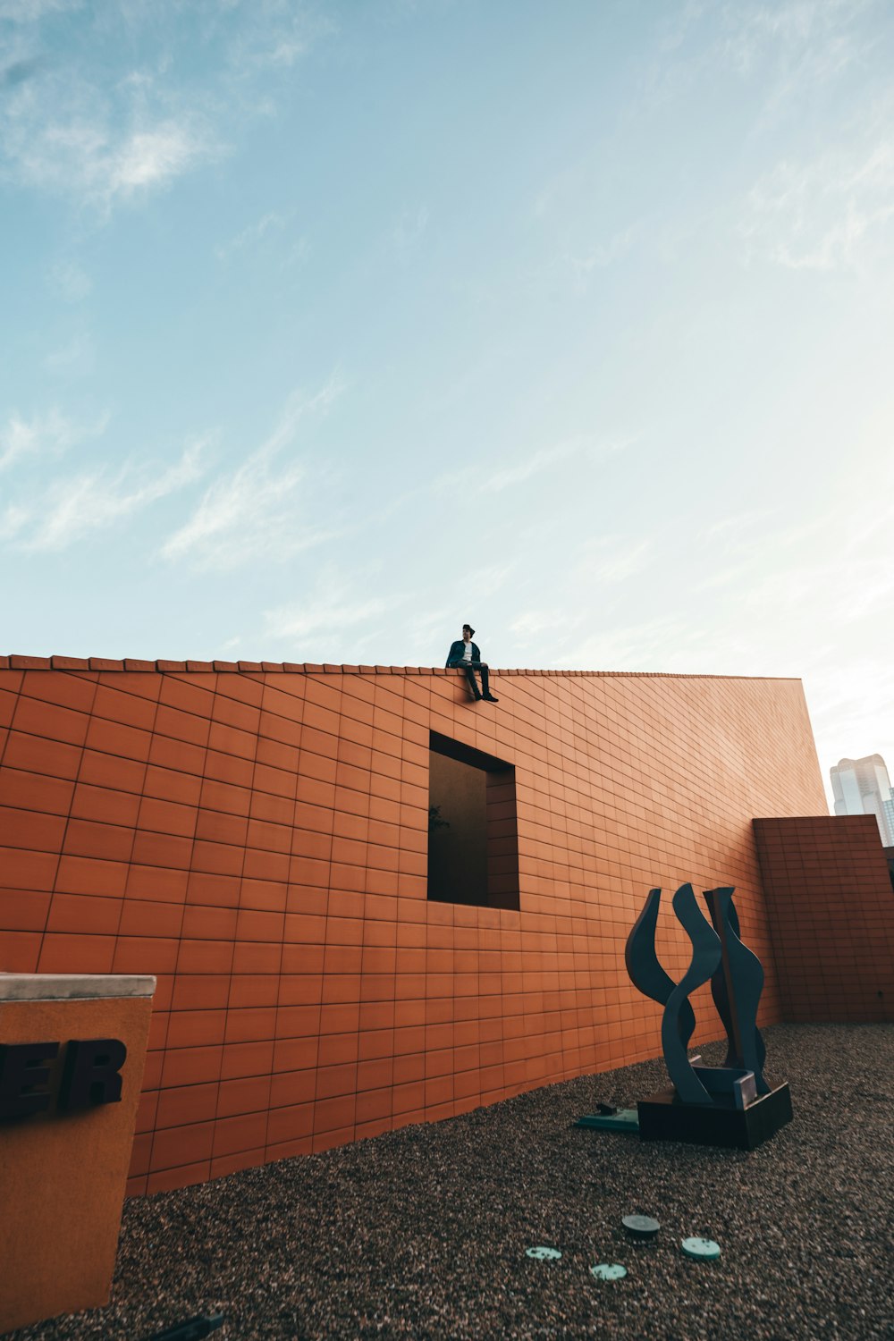 man in black jacket and black pants standing on brown concrete building during daytime