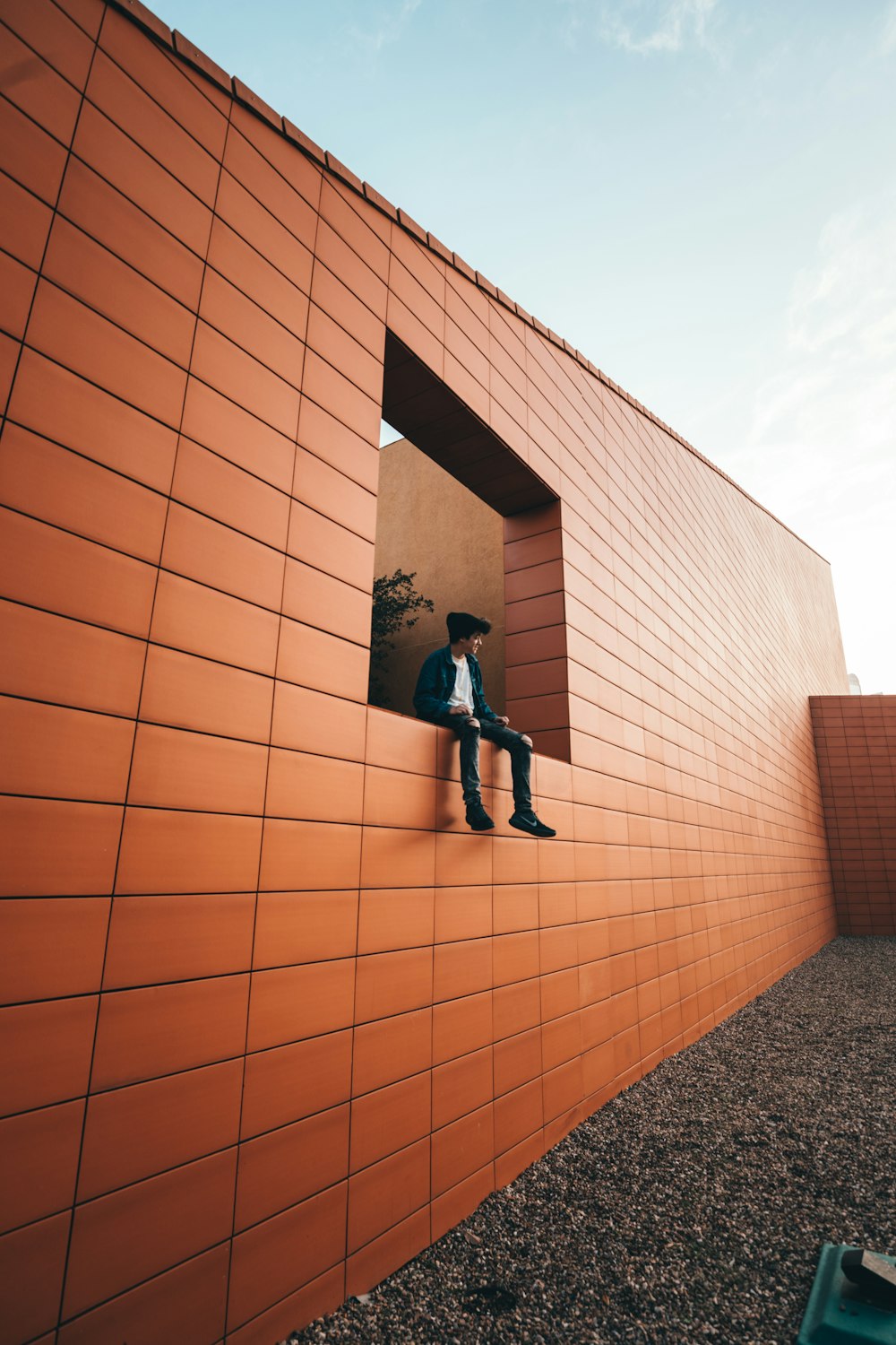 man in black jacket and black pants standing on brown brick wall during daytime