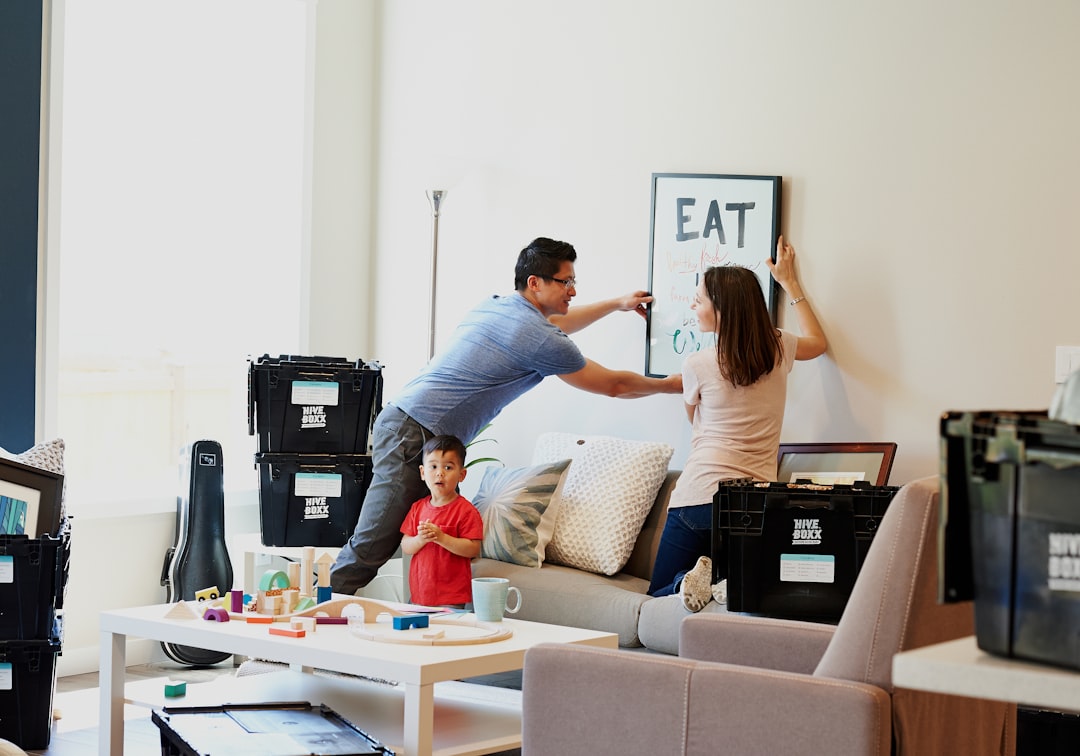 woman in blue denim jacket standing beside woman in black shirt, Hanging artwork in the new house.