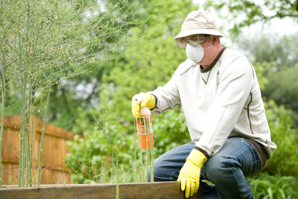 man in white long sleeve shirt and blue denim jeans sitting on brown wooden fence during