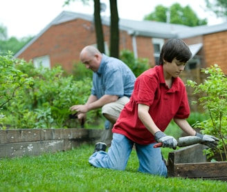 man in red polo shirt and blue denim jeans sitting on brown wooden bench during daytime