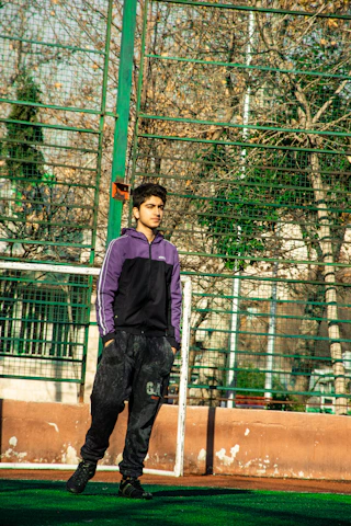 Gerald Wilcox coaching a young athlete at Nehru Stadium, Chennai, with poles and vaulting mats in the background.