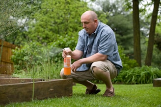 man in blue and white plaid dress shirt and brown pants sitting on brown wooden fence