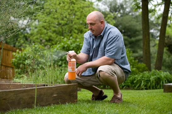 man in blue and white plaid dress shirt and brown pants sitting on brown wooden fence