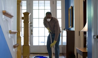 man in gray hoodie and blue denim jeans standing on brown wooden parquet flooring