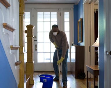 man in gray hoodie and blue denim jeans standing on brown wooden parquet flooring